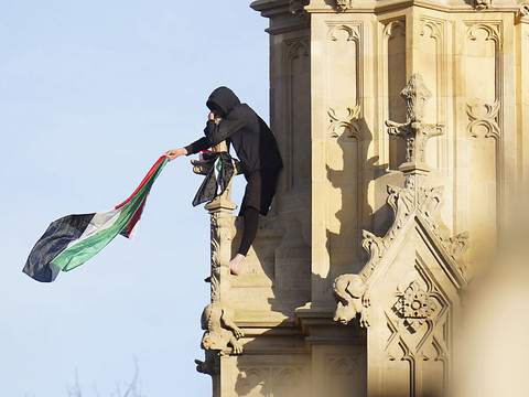 Un homme escalade Big Ben à Londres avec un drapeau palestinien