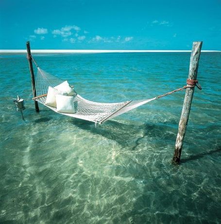 Un hamac installé sur piloti dans une eau turquoise