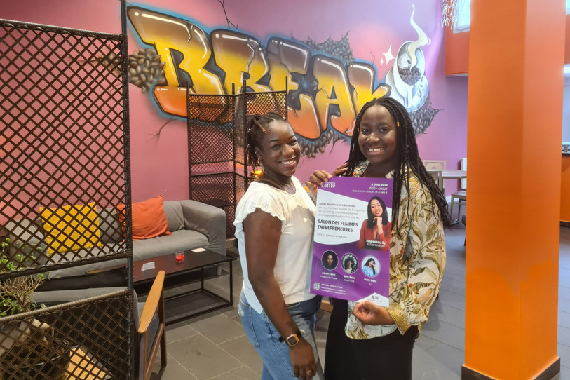 Jane Nzeza et Mélanie Mutombo, deux des trois organisatrices, posent avec l'affiche du premier salon neuchâtelois pour les femmes entrepreneures. (Photo : Association F.ame)