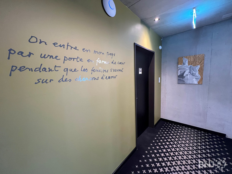 Les couloirs de l'hôtel affichent également des oeuvres. Ici, l'entrée de cette chambre est entourée d'un texte d'Alexandre Voisard et d'un tableau d'Anouk Richard.