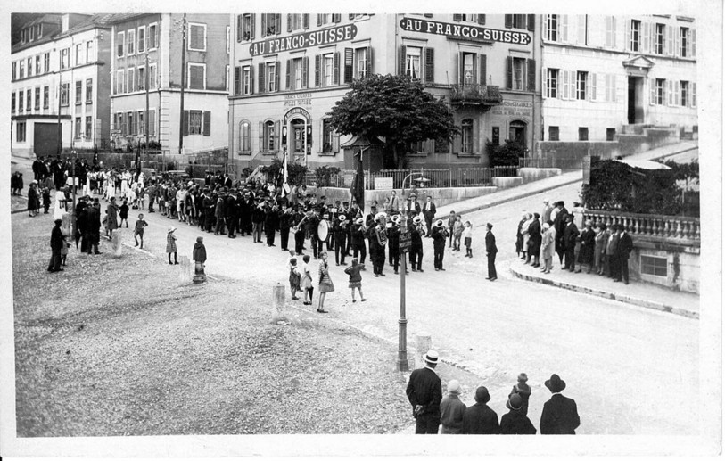 La place principale des Brenets avec le défilé d'une fanfare, au tournant du XXe siècle. (photo: collection privée, David Favre)