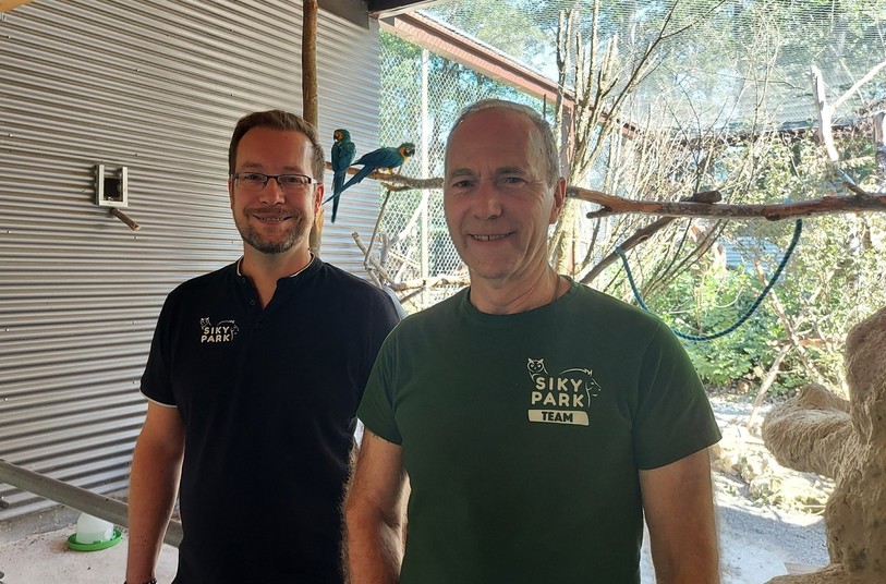 Bernard Seuret (à gauche) et Thomas Fischer, le directeur général du Sikypark et président de la nouvelle fondation, posent fièrement dans la volière remplie de perroquets.