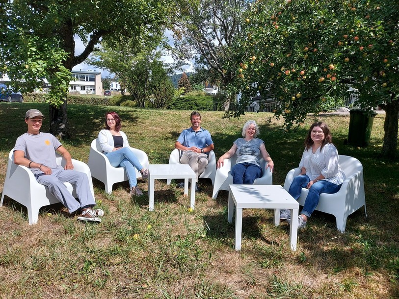 Reto Gmünder (au centre) pose dans le jardin de la Cure Bel-Air avec, de gauche à droite, Adrien Kobel, qui jouera avec son groupe Blue Gin'ger le 25 août, Melisa Ozkul, qui dédicacera sa BD à la même date, Sandra Singh de la paroisse et Laurine von Allmen du comité d'organisation. 