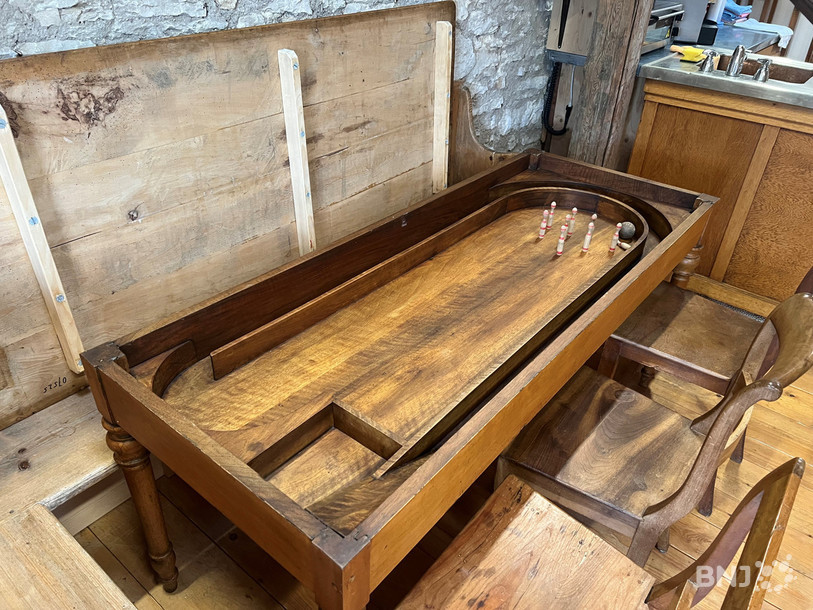 Un jeu de quilles installé dans une table. Il suffisait de lever le plateau pour accéder au jeu.