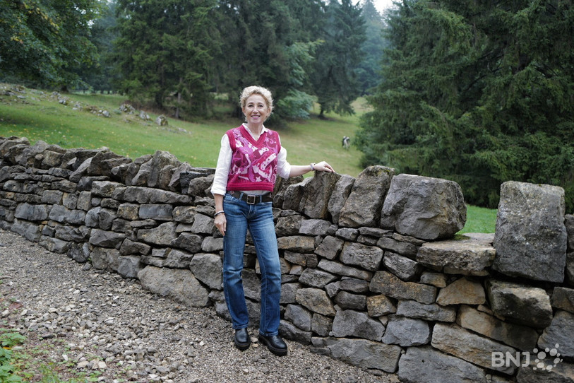 Nathalie Donzé a choisi de poser devant les sapins et le mur en pierres qui bordent sa maison, paysage typique des Franches-Montagnes.