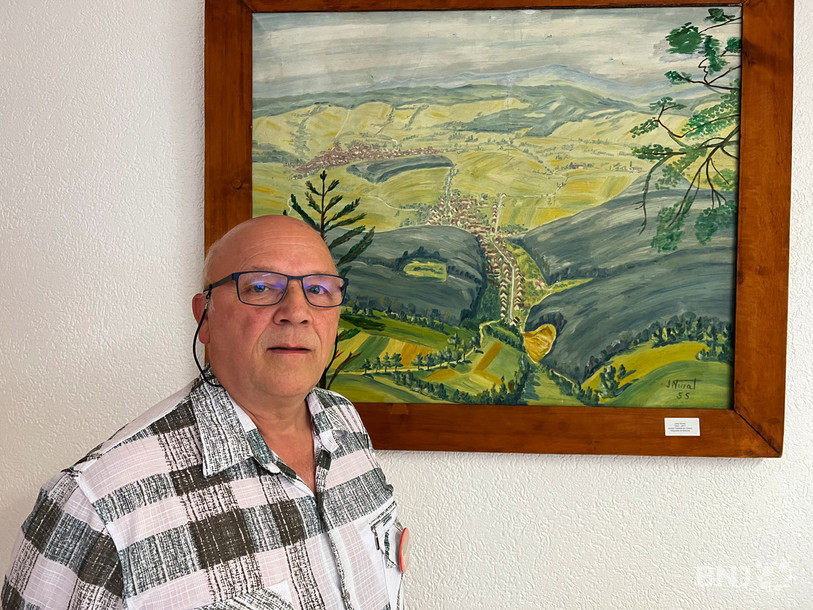 Gilles Villard, secrétaire communal depuis 41 ans, pose devant un tableau de Jules Noirat (1920-2011) représentant le village de Cornol.