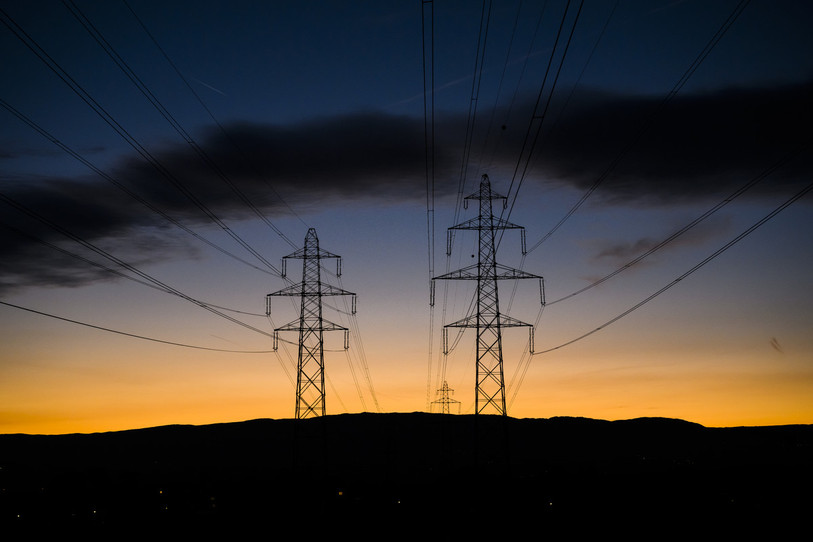 Le soleil se couche derrière les pylônes d'une ligne à haute tension. (Photo KEYSTONE/Jean-Christophe Bott)