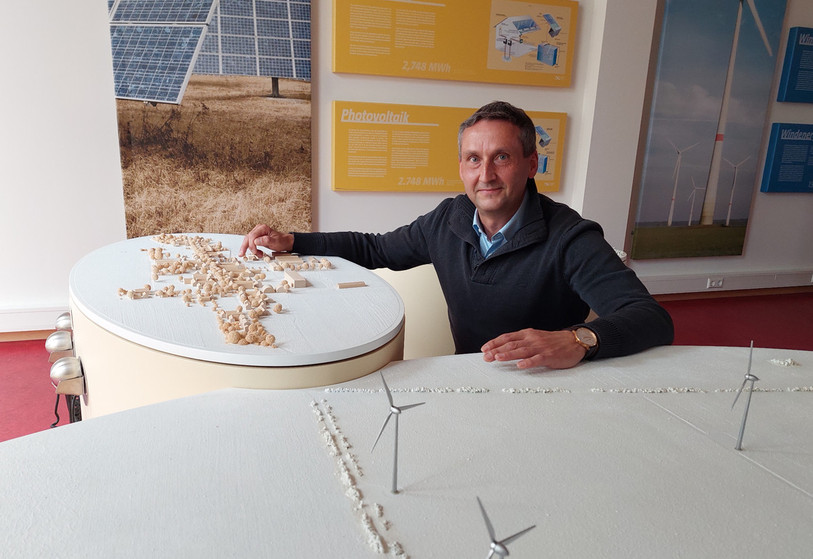 Le maire de Feldheim pose devant la maquette de son village. (Photo : Delphine Nerbollier).