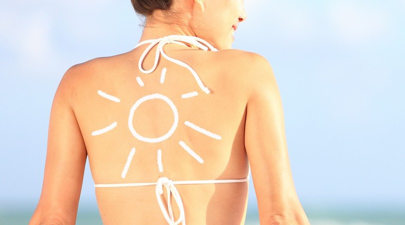 Femme de dos en maillot de bain avec de la crème solaire