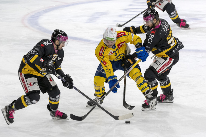 L'attaquant du HC Ajoie Thibault Frossard prend le puck au Davosien Julian Schmutz sous les yeux de Reto Schmutz (photo : KEYSTONE/Georgios Kefalas).