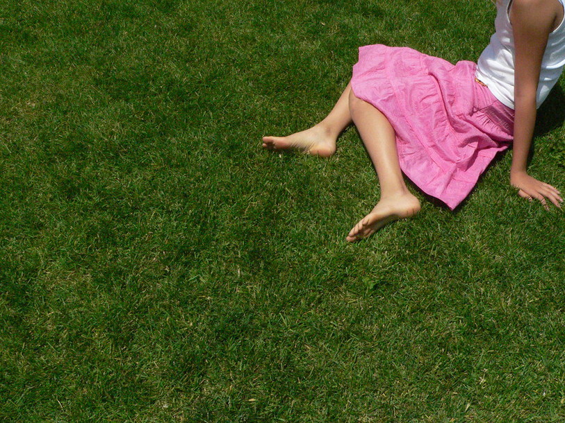 Jeune femme en jupe rose assise sur l'herbe