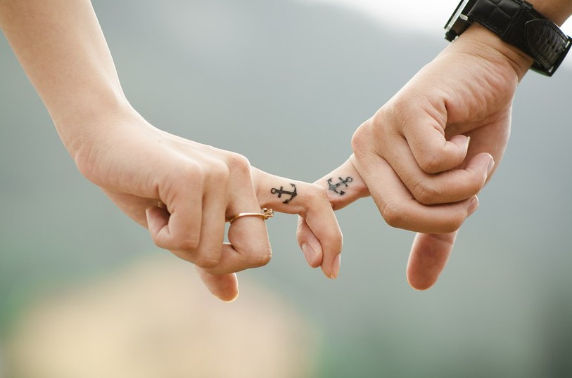 couple dont on ne voit que les mains qui se tiennent par un doigt