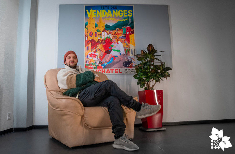Joakim Monnier, alias « L’Ange Violent », devant l’affiche officielle de la 96e édition de la Fête des vendanges de Neuchâtel (Photo : Fête des Vendanges).