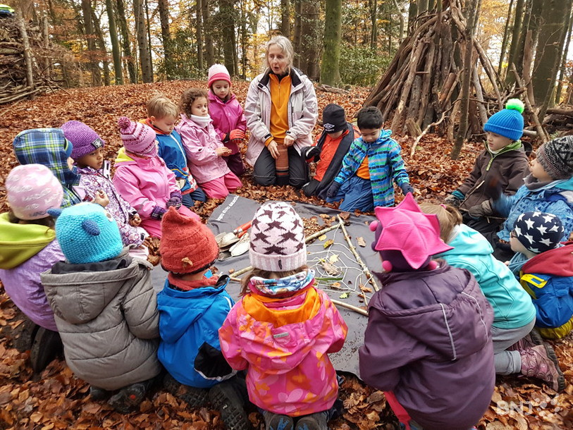 Classe d'école enfantine assis en rond dans la forêt