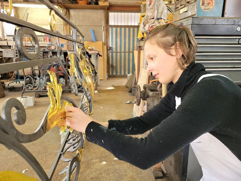 Ella Burri en pleine pose de feuilles d'or sur la barrière qui trônera devant l'Hôtel-de-Ville de Tramelan.