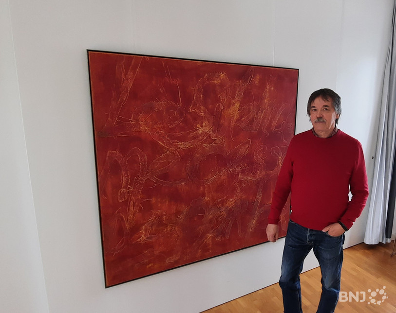 Gilles Fleury pose devant un de ses tableaux qui est exposé au Musée jurassien d'art et d'histoire.