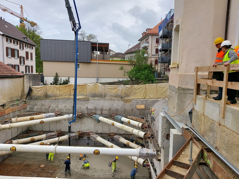 Les ouvriers commencent à couler le béton autour de l'armature ferrée pour réaliser le bâtiment d'archives sous-terrain.