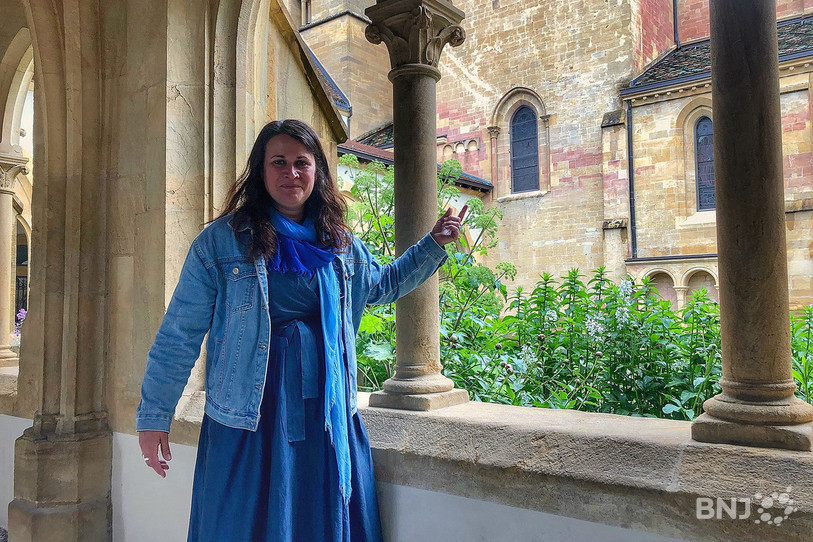 Cécile Aguillaume au cloître de la Collégiale. Elle nous montre les traces rouges sur le bâtiment, évoquées dans le reportage.