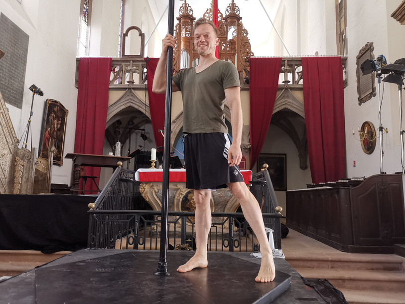 L'un des artistes pose devant sa barre de pole dance, en plein milieu de l'église. (Photo : Stéphanie Wenger)