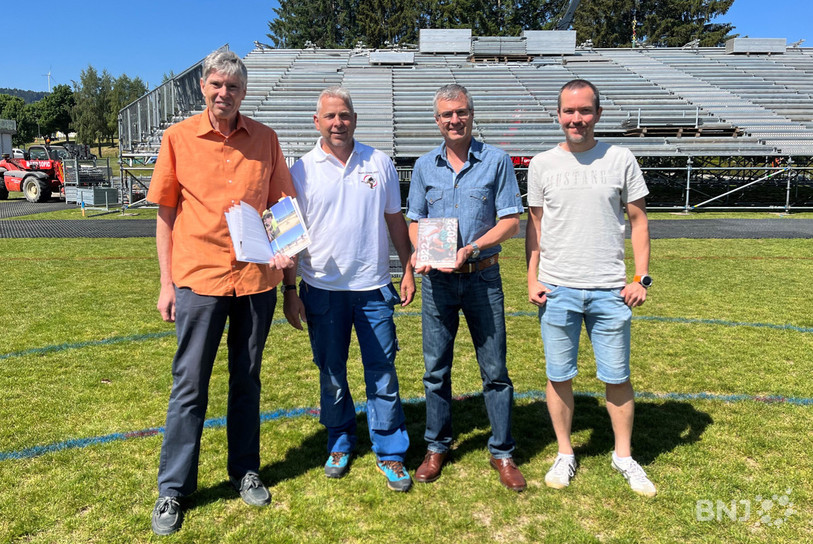 Daniel Luthi (rédacteur), Reinhard Jossen (président de l'association), Didier Wicht (responsable médias) et Yannik Bourquin (graphiste) posent devant les installations en construction pour la Fête cantonale bernoise de lutte, à Tramelan.