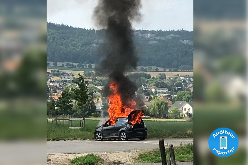La voiture a pris feu au giratoire de Rossemaison. (Photo : auditeur reporter)