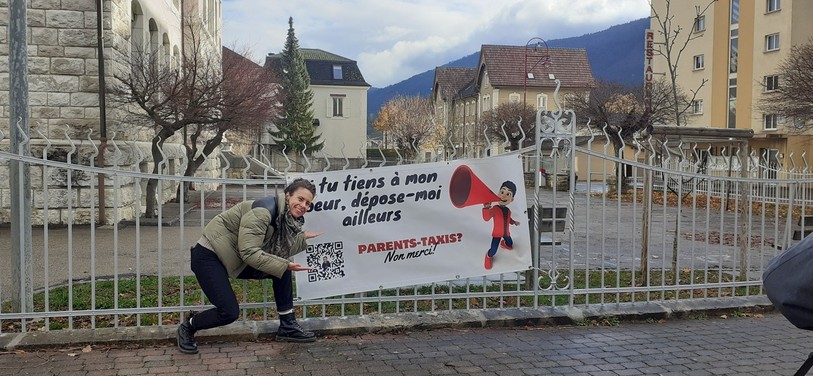 Phanee de Pool pose avec une des bâches qui met en avant les slogans créés par des élèves.