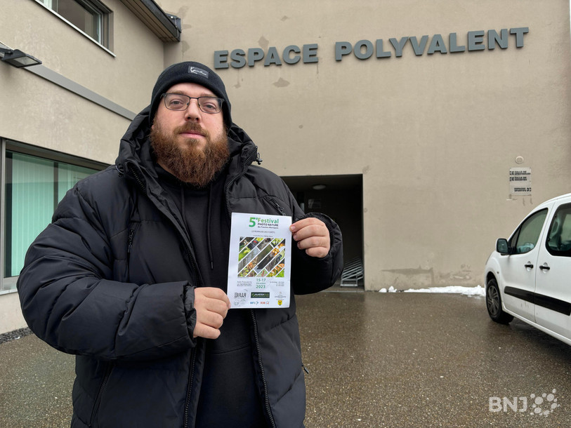 Jonathan Vallat présente l'affiche devant le nouveau lieu du festival : La Halle polyvalente du Noirmont.