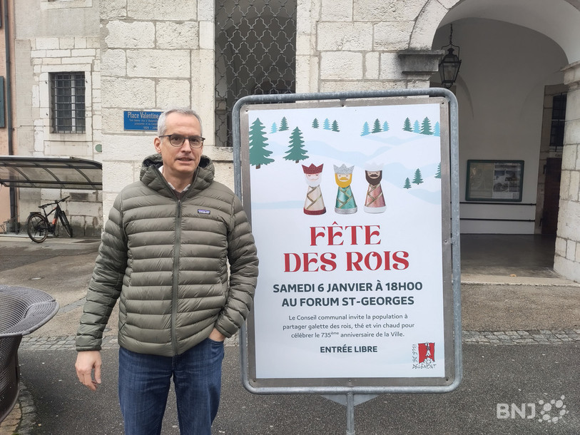 Le chancelier communal de Delémont Nicolas Guenin pose à côté de l'une des affiches annonçant la fête des rois organisée par la ville.