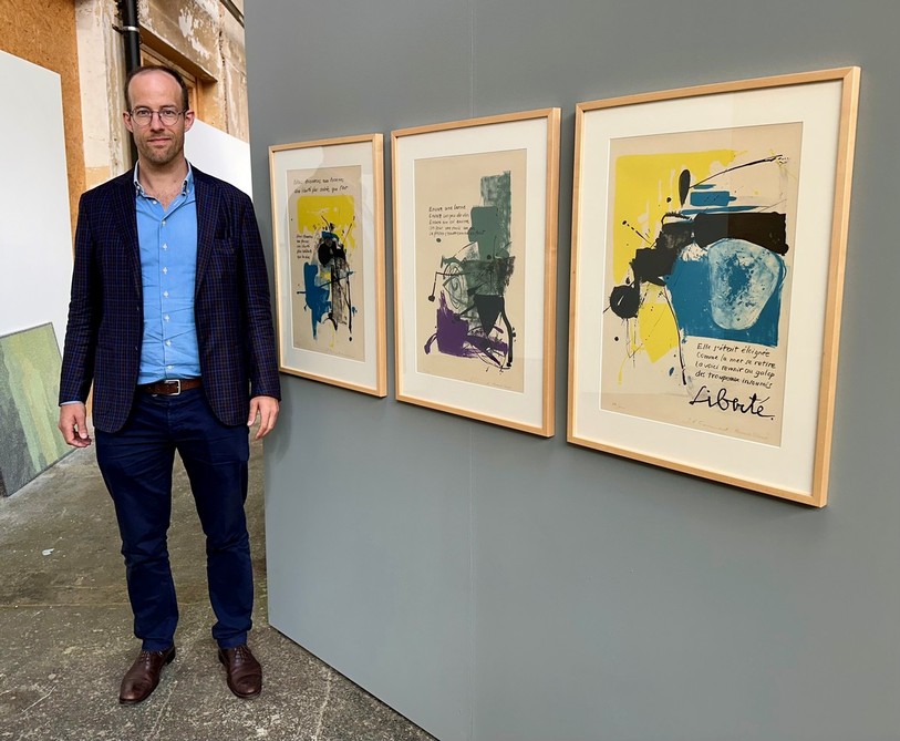 Commissaire de l’exposition « L’Art de l’Autonomie », Yves Guignard pose aux côtés de lithographies de Jean-François Comment accompagnées de textes d’Alexandre Voisard réalisées en 1970.