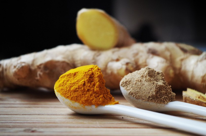 Une cuillière contenant du curcuma et une autre contenant du gingembre