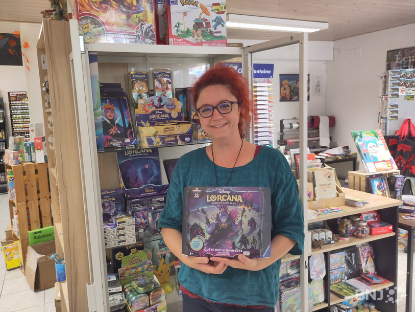 Marielle Chevrolet, de la librairie Mille et une Histoires, pose ici avec des cartes Disney Lorcana.
