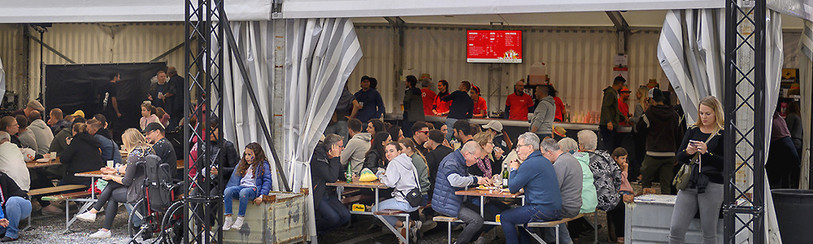 Du monde assis aux tables de la tente RTN à la Fête des Vendanges 2023