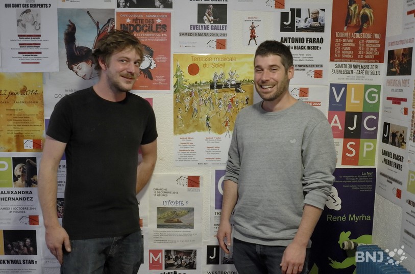 Thomas Queloz et Jérôme Gogniat au milieu d'affiches de concerts...