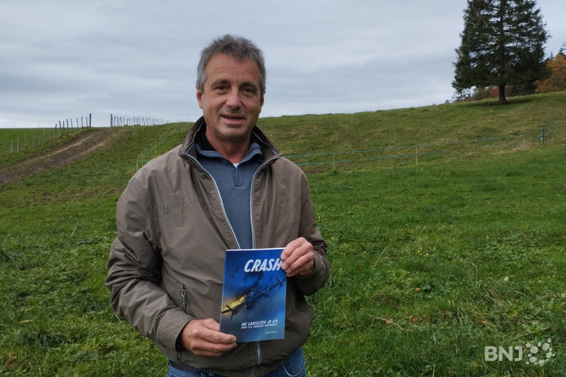 Dimitri Viglietti au Chaumont, sur le lieu exact de l’impact, tenant son livre « Crash du Lancaster JB 474 dans les Franches-Montagnes ».