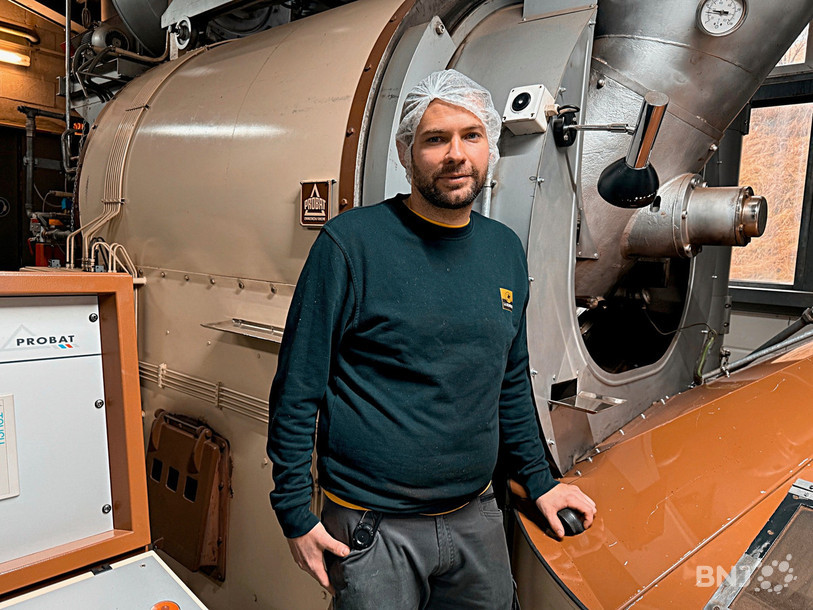 Dans les locaux de La Semeuse à La Chaux-de-Fonds, le torréfacteur, Julien Cuche, devant le torréfacteur, la machine.