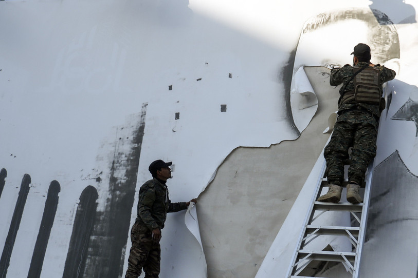 Une photo de Bachar Al-Assad est enlevée de la façade de l'aéroport international d'Alep. (Photo : AP / Omar Albam).