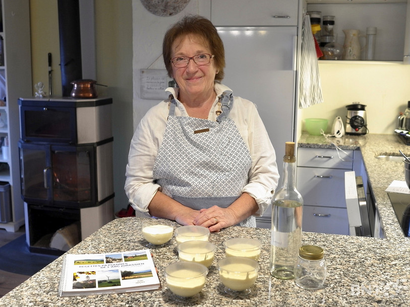 Yvette Petermann avec les petites coupes de parfait à la Damassine et le livre des recettes paysannes de l’arc jurassien.