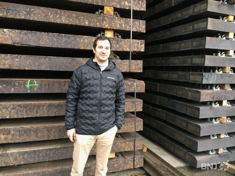 Benjamin Corbat, co-directeur du Groupe Corbat, pose devant de nouvelles et d'anciennes traverses de chemin de fer. Ces dernières devraient permettre d'alimenter le futur site de production d'hydrogène.