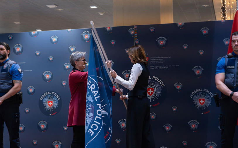 Après plus de dix ans à son poste, Nicoletta della Valle (à gauche), directrice sortante de Fedpol, a symboliquement remis le drapeau de Fedpol à la nouvelle directrice, Eva Wildi-Cortés (à droite). (Photo : Services du Parlement).