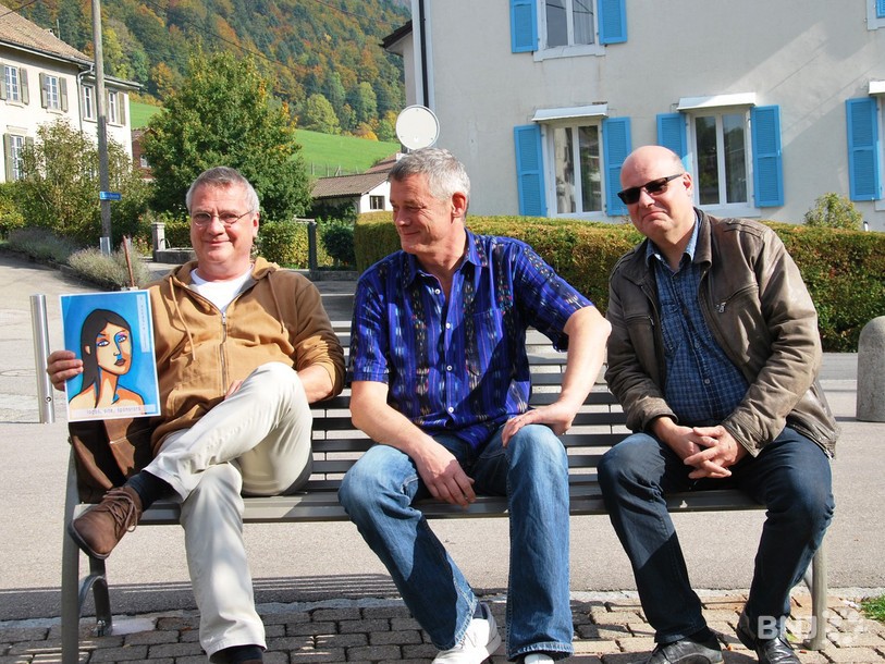 Serge Brachetto, alias Brac, et son affiche, Thomas Loosli, membre du comité du fOrum culture, et Gérard Py, maire de Cormoret, une des premières communes à participer