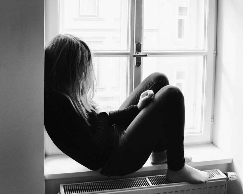 adolescente assise sur le rebord d'une fenêtre