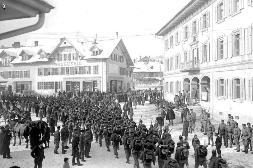 Des soldats en armes marchent à travers Tavannes durant la Première Guerre mondiale. Image : Archives fédérales.