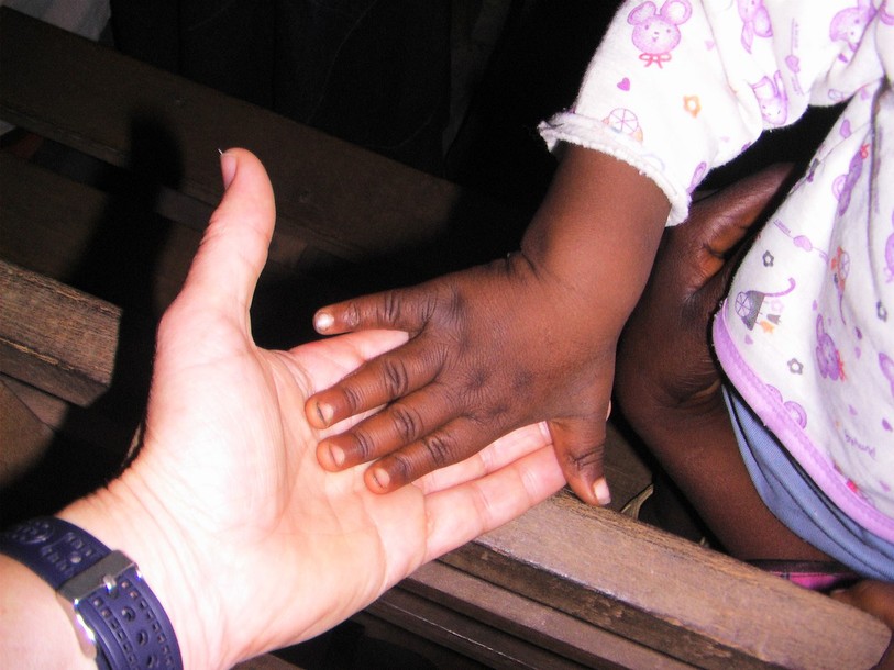 Une main blanche qui se tend vers une main noire