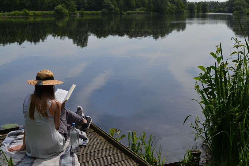 Jeune femme qui lit au bord de l'eau