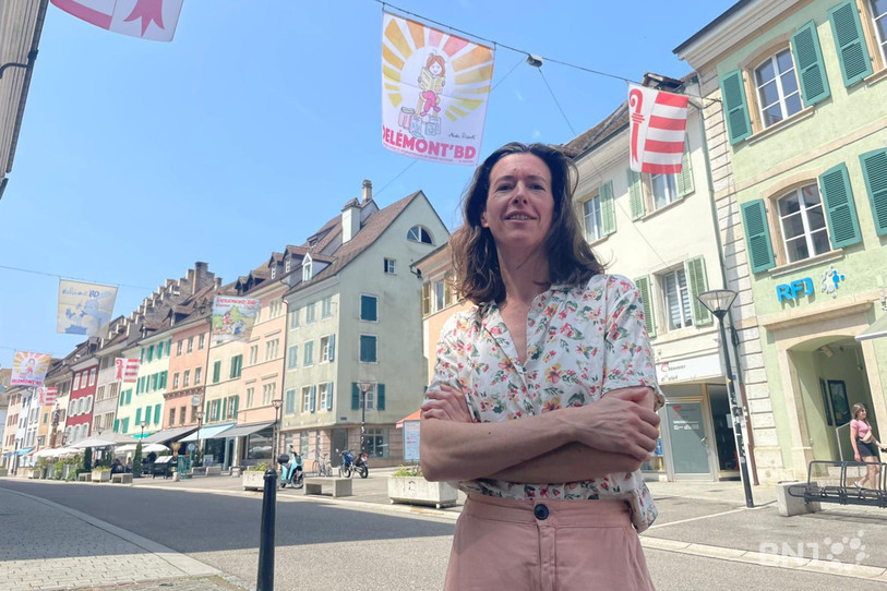 La Grande Trissoue de cette édition, Aude Picault, pose devant son illustration en vieille ville de Delémont.