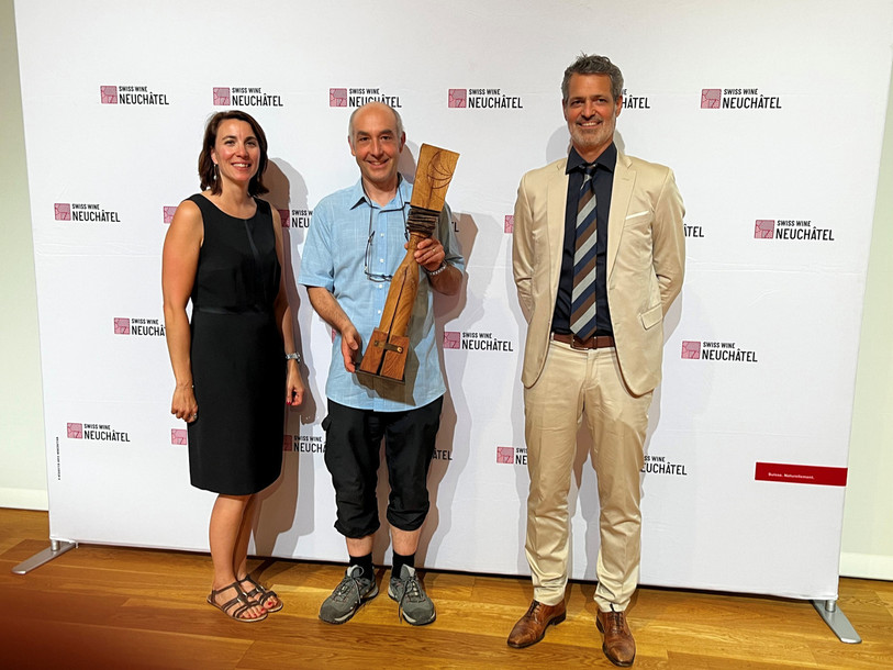 Mireille Bühler, directrice de Neuchâtel Vins et terroir, et Yann Huguelit, directeur de la CNAV, entourent Jean-Marc Jungo, de la cave des Lauriers, avec le trophée d’Ambassadeur. (Photo : Neuchâtel - Vins et terroir).