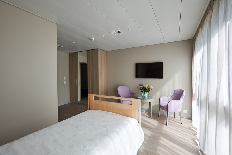 Photo d'une petite chambre à coucher pour personne seule disposant d'un lit, d'une table et deux chaises ainsi qu'une télévision et une armoire.