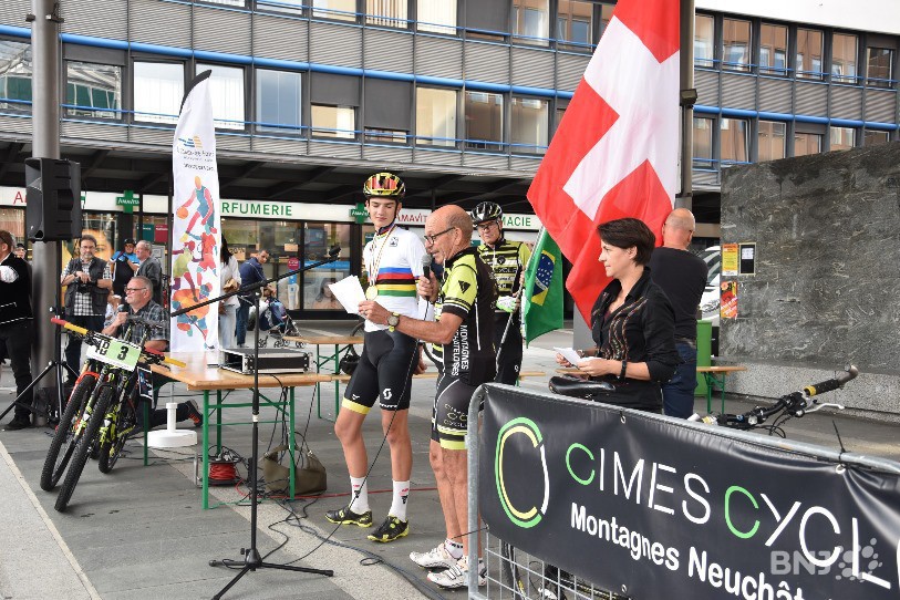 Alexandre Balmer sur l'estrade de la place Espacité lors de la cérémonie officielle mercredi soir, en compagnie d'Yves Huguenin, vice-président de Cimes Cycle, et Katia Babey, conseillère communale en charge des sports.