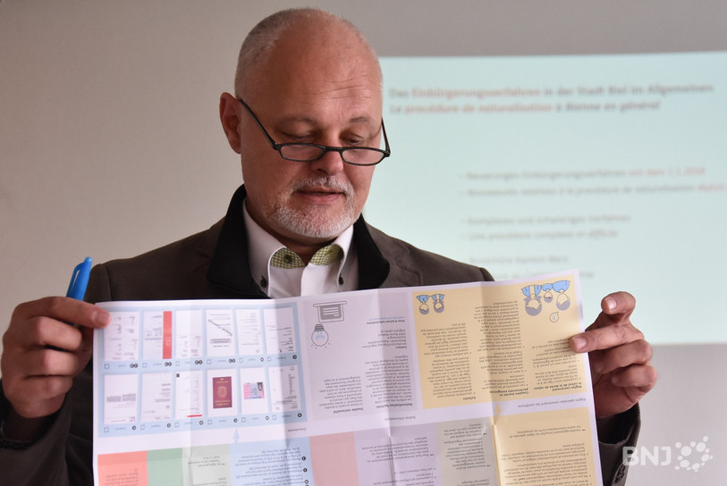 André Glauser, le responsable du département de la sécurité publique de Bienne, a le regard posé sur la nouvelle brochure qui explique le processus de naturalisation.