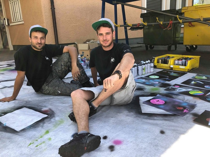 L'artiste Saype (à gauche) et Lionel, membre de son équipe et ancien camarade de classe.